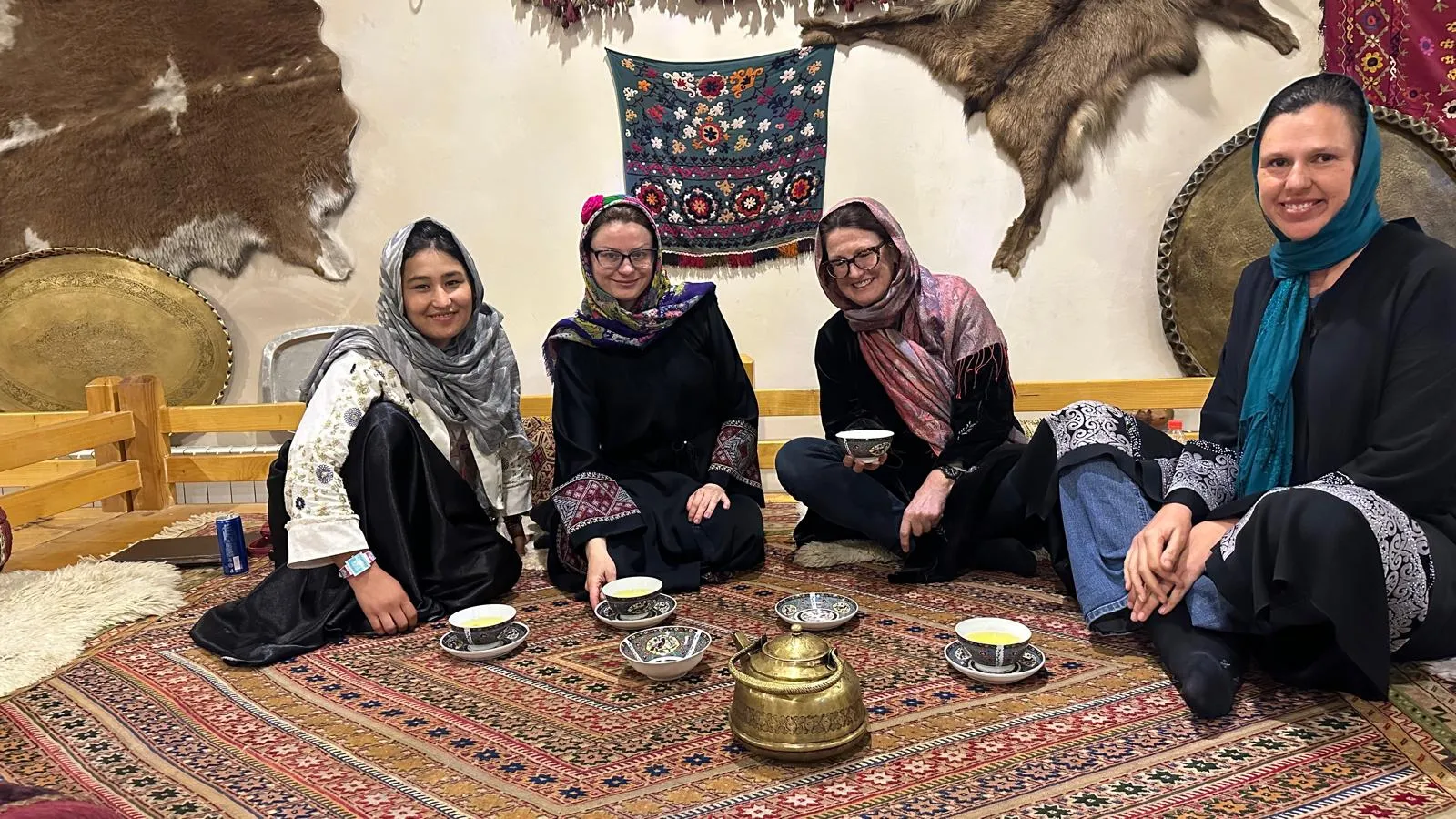 Female travelers with their local female tour guide in a traditional restaurant in Kabul, sharing tea together.